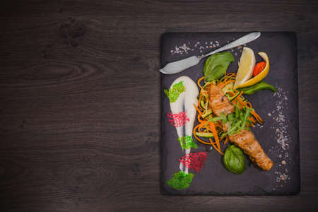 Salmon steak with lemon greens and sauce on stone with salt.の写真素材