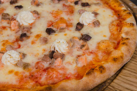 Hot piece of pizza with melted cheese on a rustic wooden table.の写真素材