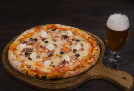 Hot piece of pizza with melted cheese on a rustic wooden table and beer.の写真素材
