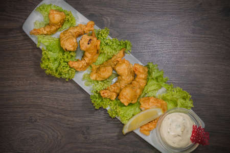 Fried prawns on a plate with sauce and on a wooden background.の写真素材