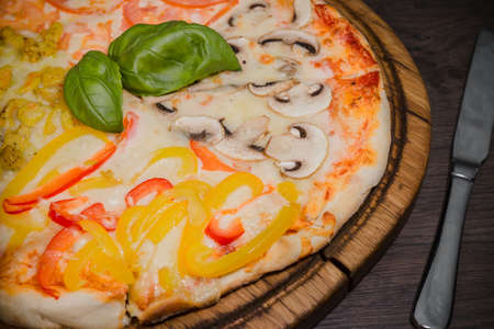 Hot piece of pizza with melted cheese on a rustic wooden table.の写真素材
