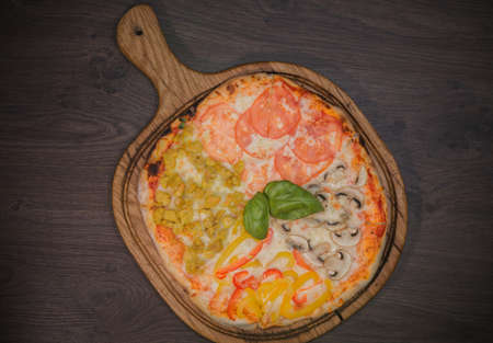 Hot piece of pizza with melted cheese on a rustic wooden table.の写真素材