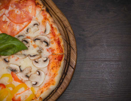 Hot piece of pizza with melted cheese on a rustic wooden table.の写真素材
