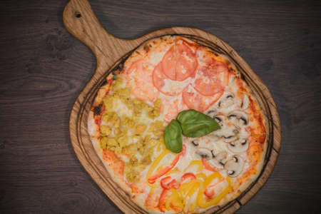 Hot piece of pizza with melted cheese on a rustic wooden table.の写真素材