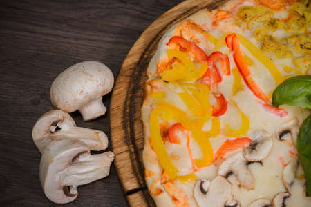 Hot piece of pizza with melted cheese on a rustic wooden table.の写真素材
