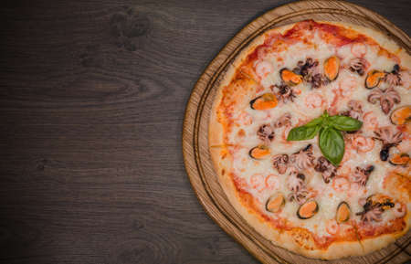 Hot piece of pizza with melted cheese on a rustic wooden table.の写真素材