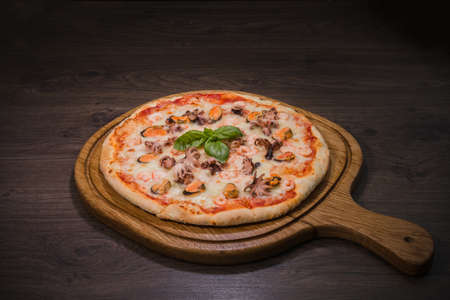 Hot piece of pizza with melted cheese on a rustic wooden table.の写真素材
