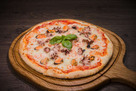 Hot piece of pizza with melted cheese on a rustic wooden table.の写真素材