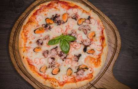 Hot piece of pizza with melted cheese on a rustic wooden table.の写真素材
