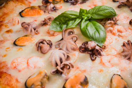 Hot piece of pizza with melted cheese on a rustic wooden table.の写真素材