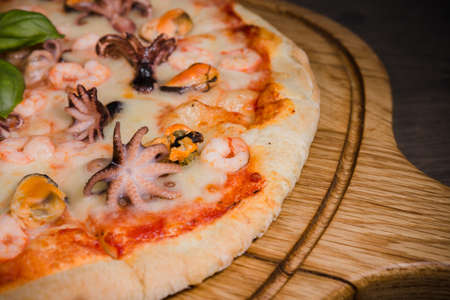 Hot piece of pizza with melted cheese on a rustic wooden table.の写真素材