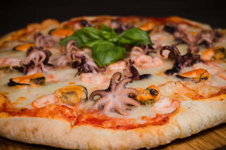 Hot piece of pizza with melted cheese on a rustic wooden table.の写真素材