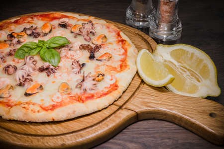 Hot piece of pizza with melted cheese on a rustic wooden table.の写真素材
