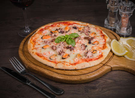 Hot piece of pizza with melted cheese on a rustic wooden table.の写真素材