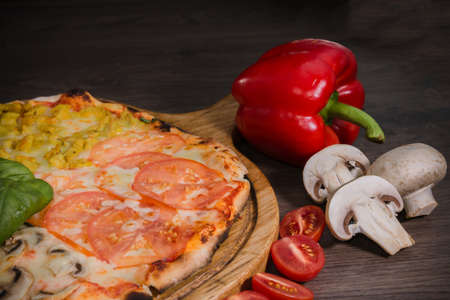 Hot piece of pizza with melted cheese on a rustic wooden table.の写真素材
