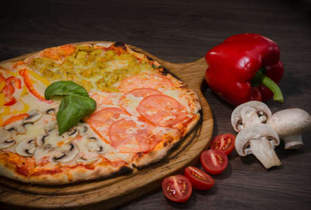 Hot piece of pizza with melted cheese on a rustic wooden table.の写真素材