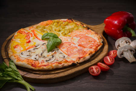 Hot piece of pizza with melted cheese on a rustic wooden table.の写真素材