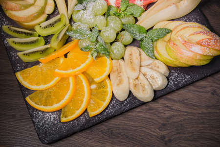 Fruit slicing on a wooden background and on a stone stand.の写真素材