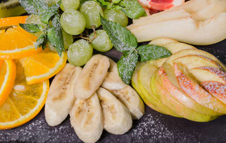 Fruit slicing on a wooden background and on a stone stand.の写真素材