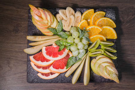 Fruit slicing on a wooden background and on a stone stand.の写真素材