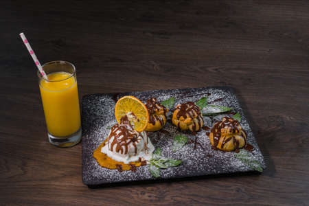 A ball of ice cream on a stone background with an orange glass of juice.の写真素材