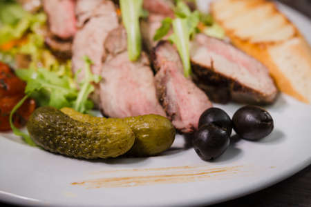 Roasted meat with blood in a cut with vegetables on a wooden background.の写真素材