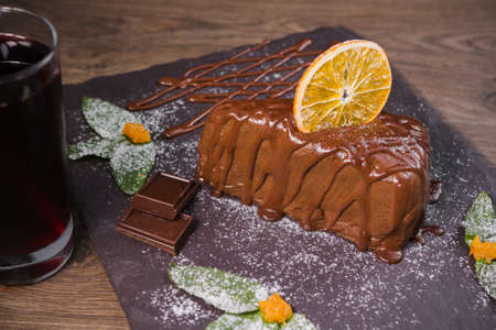 Chocolate dessert with orange chips on a wooden background.