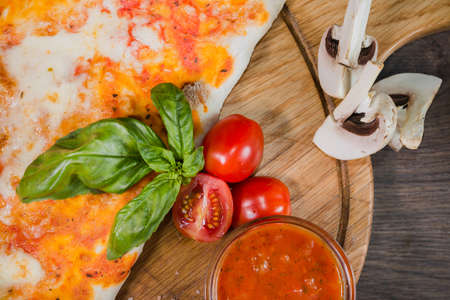 Hot piece of pizza with melted cheese on a rustic wooden table.の写真素材