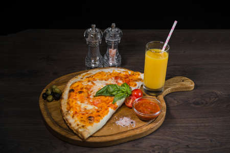 Pizza on a wooden surface with seasonings and fresh juice.の写真素材