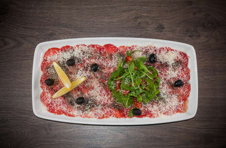 Sliced sausage on a white plate with cheese and lemon.の写真素材