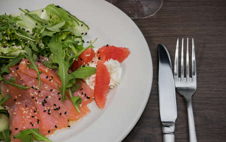 Meat of trout on a plate with vegetables and grapefruit.の写真素材