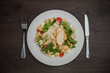 Caesar salad in a white plate on a wooden background.の写真素材