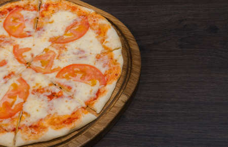Hot piece of pizza with melted cheese on a rustic wooden table.の写真素材