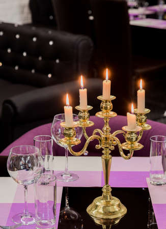 Glasses and a candlestick on a glass table in a restaurant. Romantic settingの写真素材