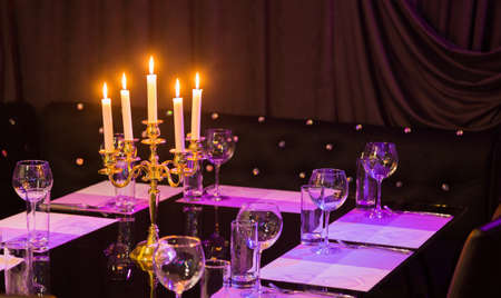 Glasses and a candlestick on a glass table in a restaurant. Romantic settingの写真素材