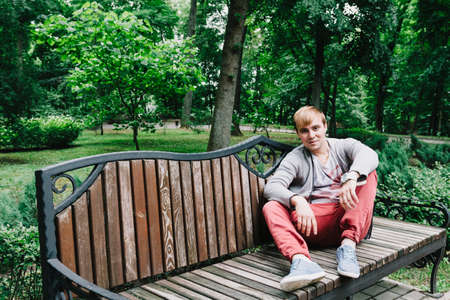 Portrait of a stylish man on a bench in the park.