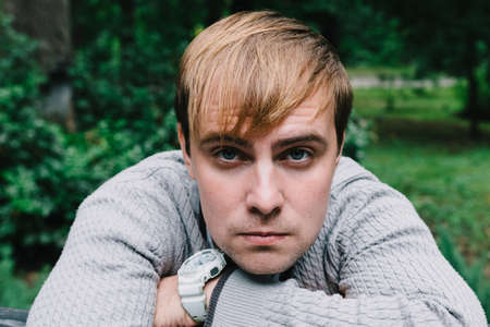 Portrait of a stylish man on a bench in the park.の写真素材