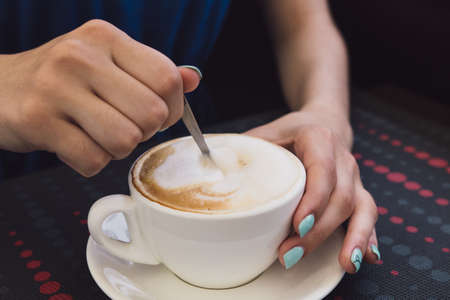 A very beautiful business woman sits in a cafe and holds a cup of coffee in her handsの写真素材