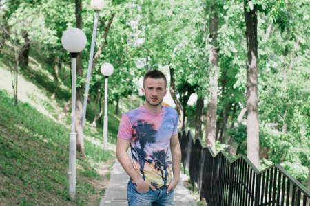Portrait of a handsome young man in a clear sunny day. Green trees