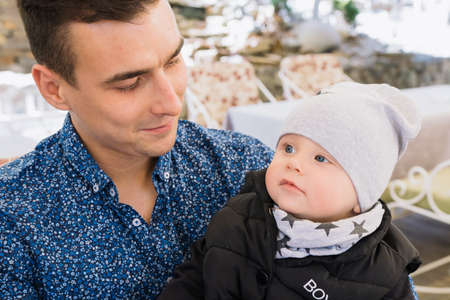 A happy married couple is sitting in a cafe and enjoying this time. They play with their child, he...