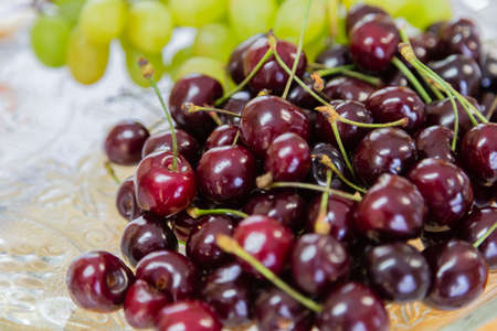 Close up of pile of ripe cherries with stalks and leaves. Large collection of fresh red cherries....