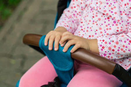 Little girl is sitting in a pram in a beautiful parkの写真素材
