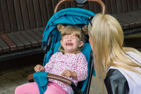 Mother walking while pushing a stroller in the parkの写真素材