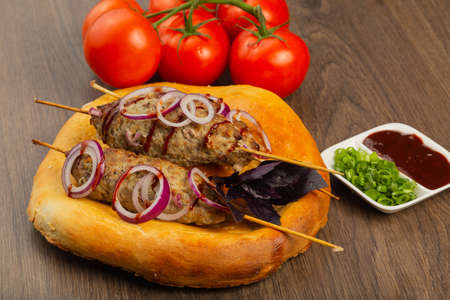 Lulya-kebab. Shish kebab on a stick, minced meat. Traditional Caucasian dish. On a cutting board, with green salad, ketchup, spicesの写真素材