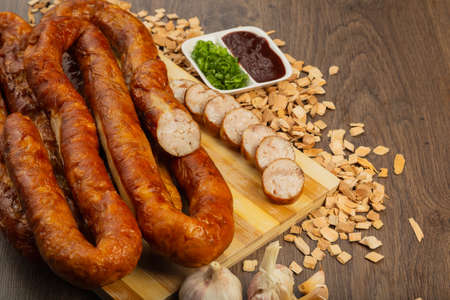 Homemade sausage on a wooden background with seasonings and sauce.