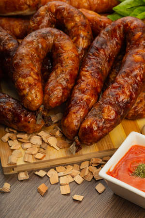 Homemade sausage on a wooden background with seasonings and sauce.