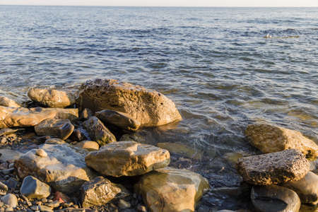 Sea waves are fighting against the big rocks on the shore.