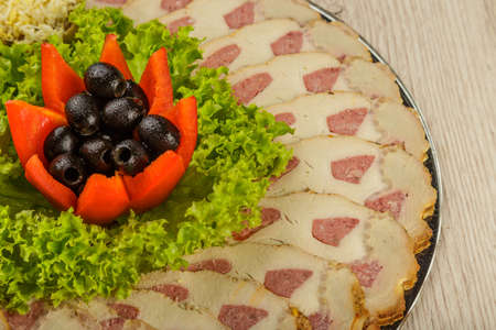 Meat sliced on a mirror dish decorated with verdure.