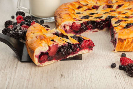Berry pie on a wooden background with ingredients.