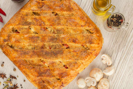 Meat pie on a wooden background with ingredients.